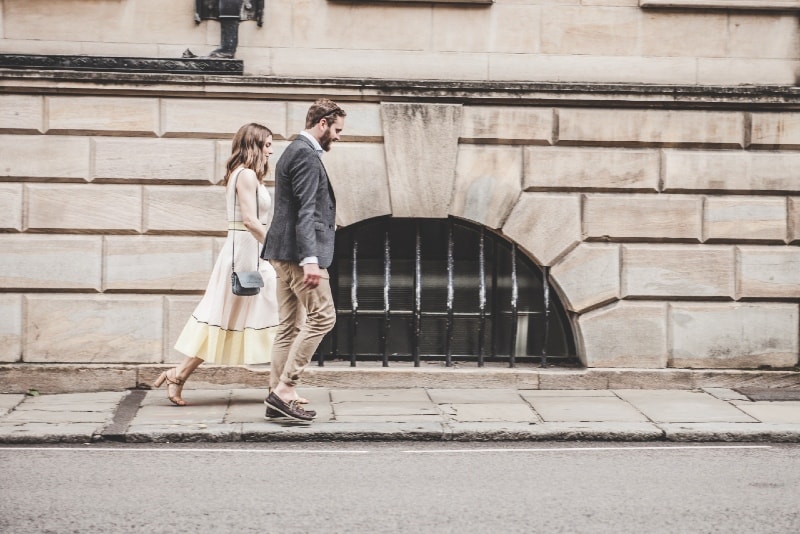 man en vrouw die hand in hand lopen langs de weg