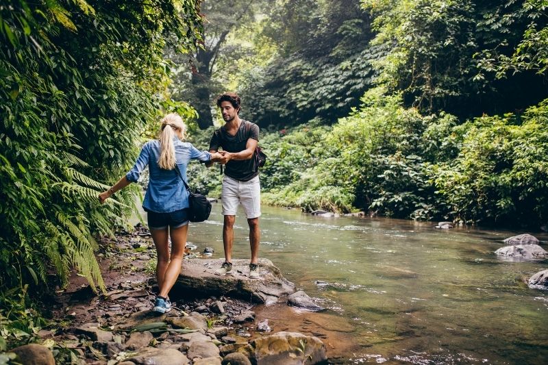 Paar, das in den Felsen am Bach im Wald spazieren geht 