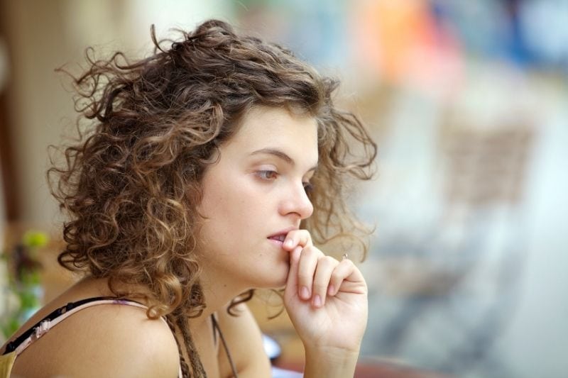 curly short haired woman deep thinking and biting her nail