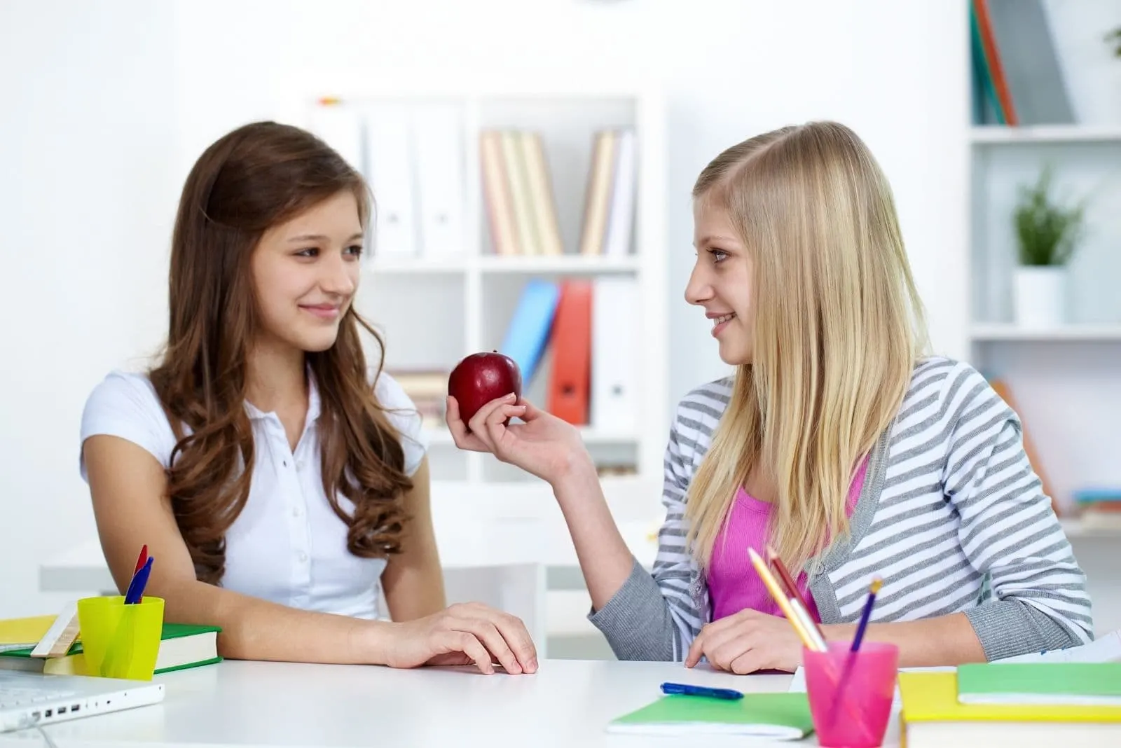 cute beautiful lady giving apple to classmate in an art class