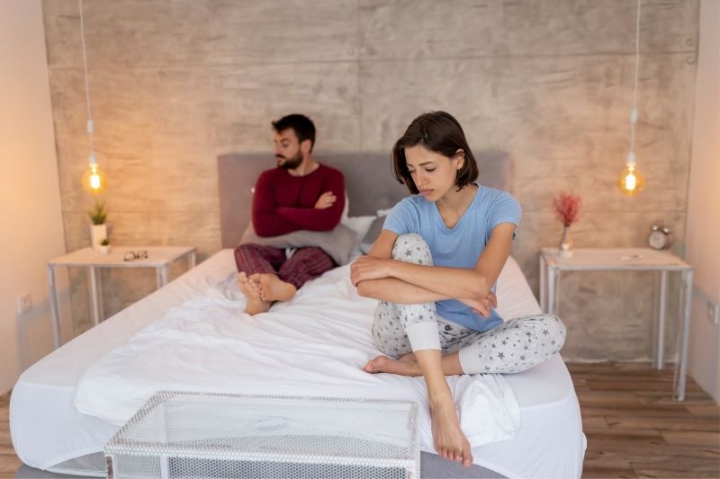 displeased couple having problem with marriage sitting on the bed