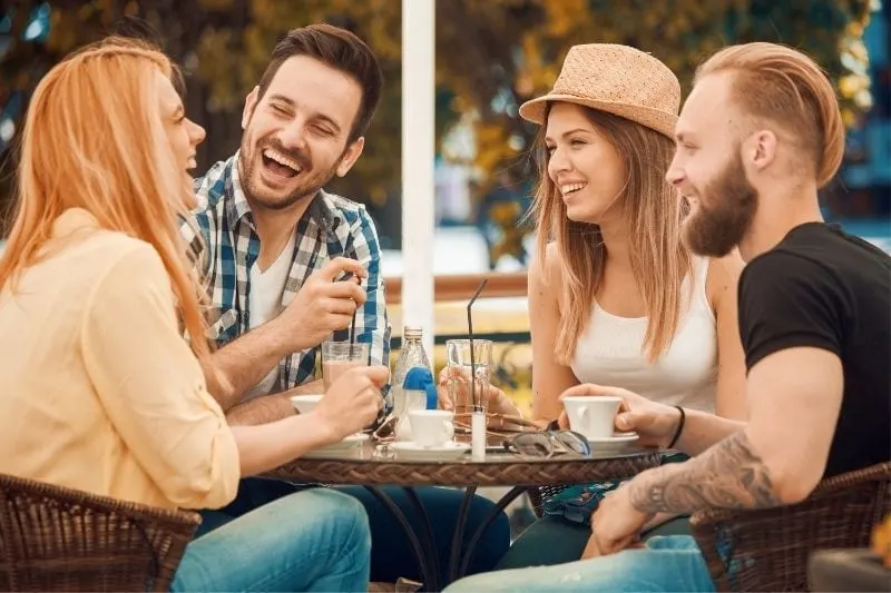 four friends chatting in an outdoor cafe laughing 