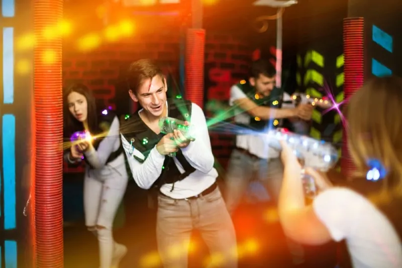 friends holding laser pistols playing laser tag