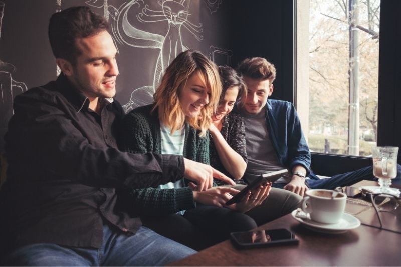 grupo de amigos charlando en el cafe y mirando internet dentro del cafe