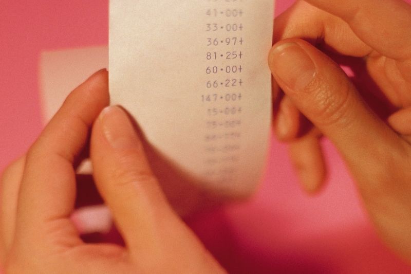 hand of a woman holding a receipt froma cash register