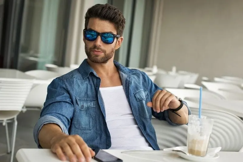 handsome man in sunglasses sitting and dining in restaurant alone