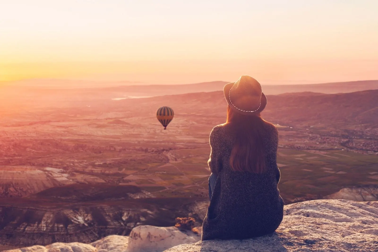 image of woman on top of a mountain admiring the balloons in the air