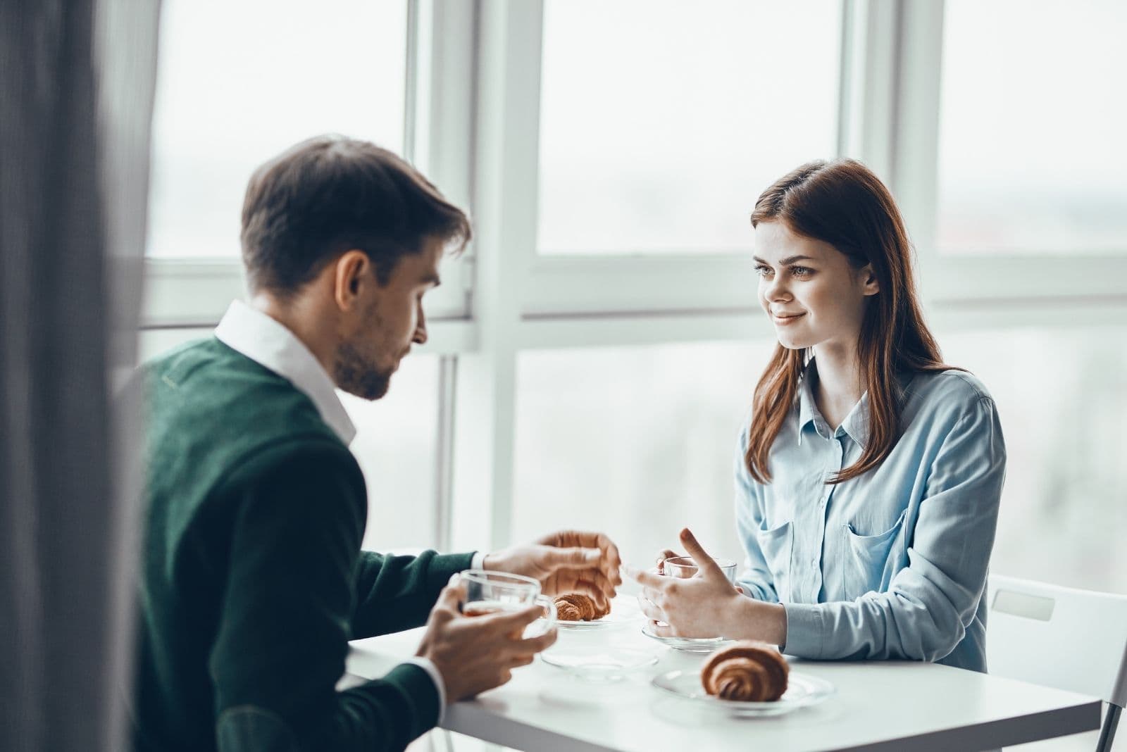 man and woman having breakfast inside a cafe talking 
