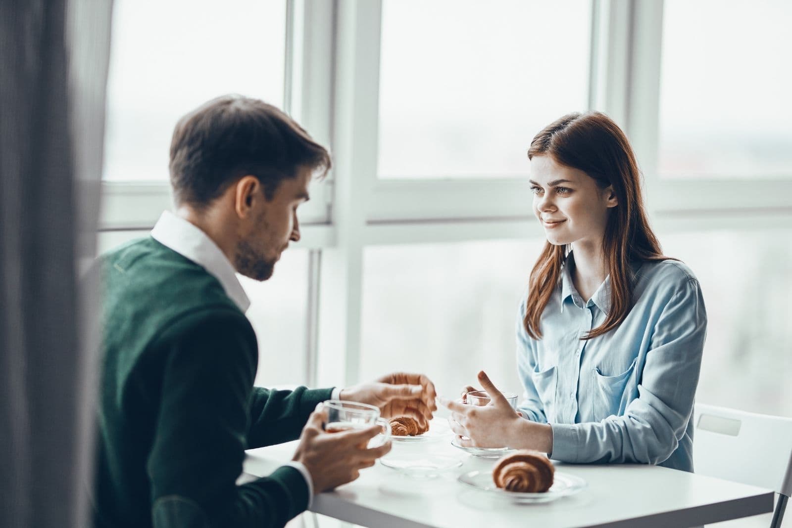 hombre y mujer desayunando dentro de una cafeteria hablando 