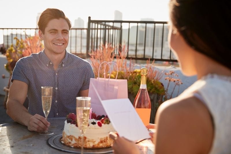 man die een vrouw cadeau geeft tijdens een date in een buitenrestaurant