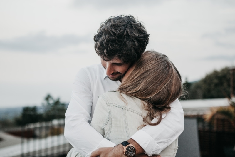 man in white shirt hugging woman outdoor