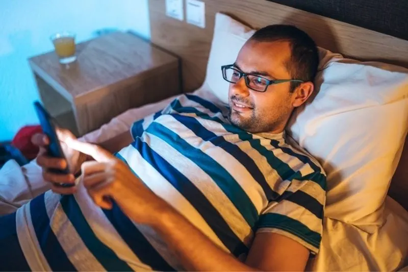 man reading messages from his smartphone while lying on bed
