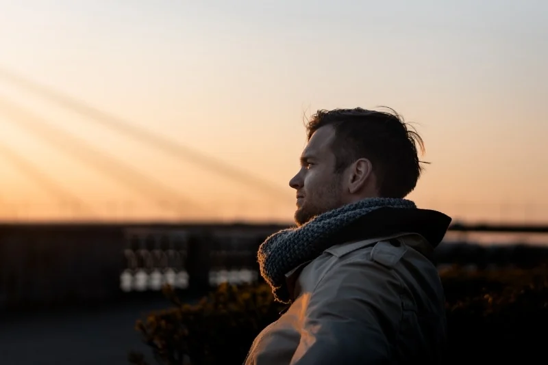man with gray knit scarf standing outdoor during golden hour
