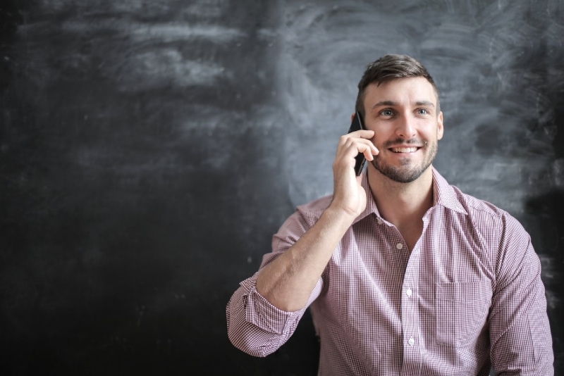 man talking on the phone while standing near wall