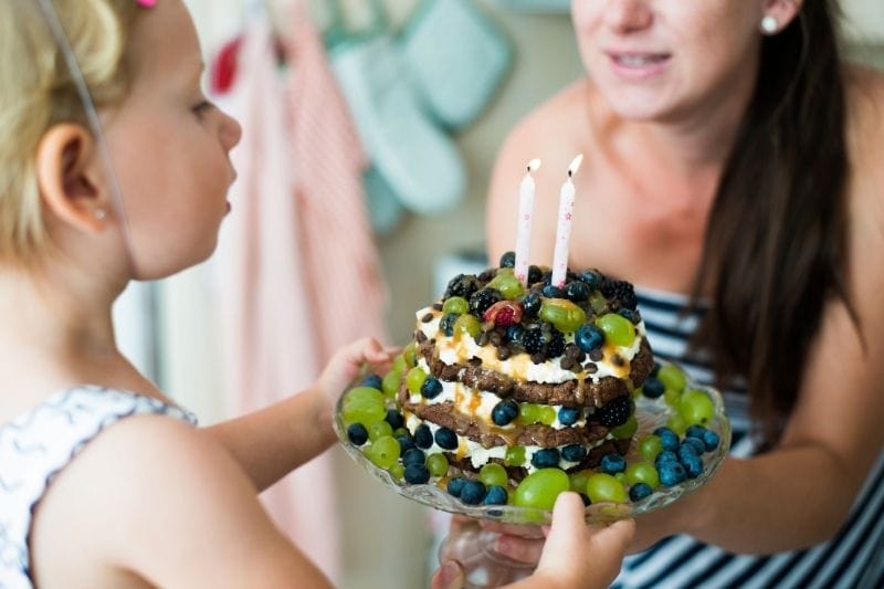 mother giving birthday cake to her cute daughter 