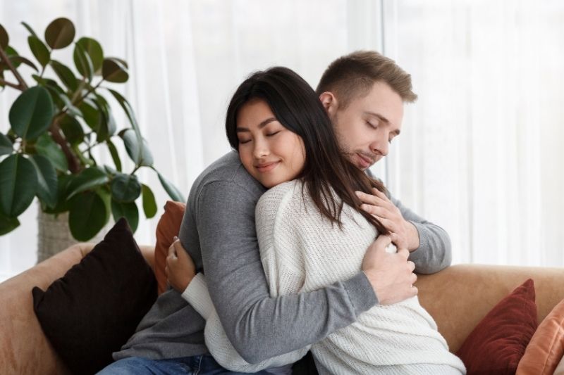 multicultural couple hugging reconciling after a quarrel at home