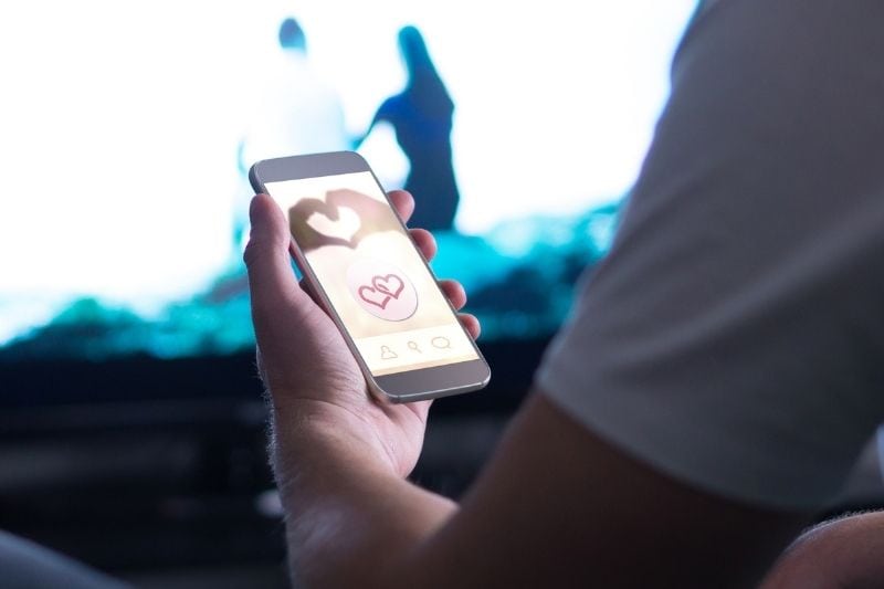 aplicación de citas en línea en la pantalla del teléfono inteligente sostenido por un hombre en imágenes recortadas.