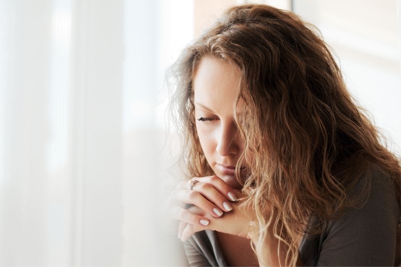 mujer triste y pensativa cerca de las ventanas