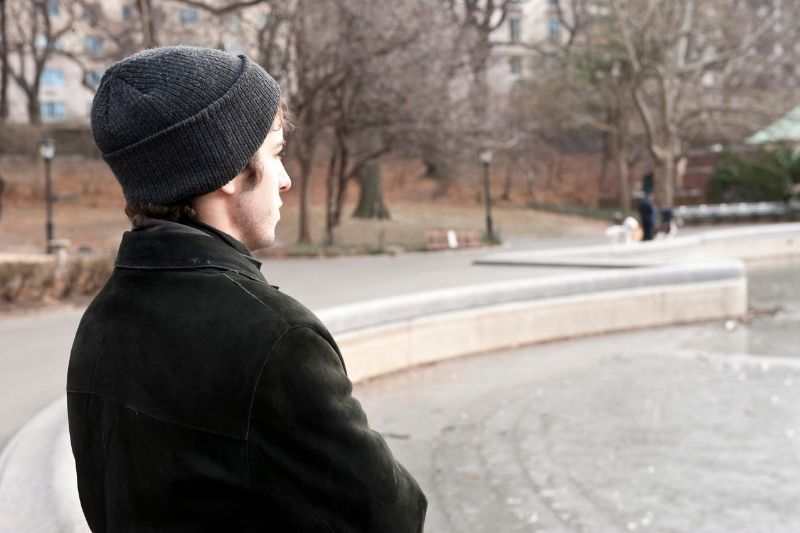 pensive young man standing at the central park new york