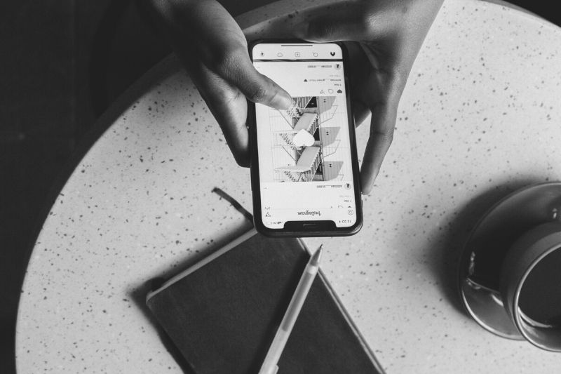 persona che tiene in mano uno smartphone con l'applicazione Instagram in una fotografia in bianco e nero