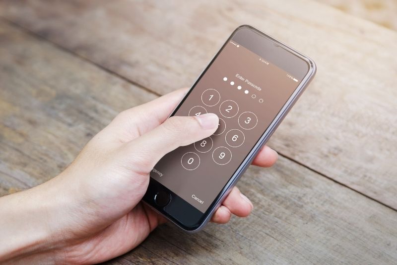 person tapping on passcode on the cellphone on top of a table