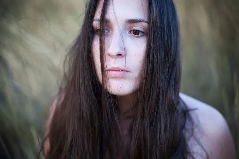 portrait of a woman introspecting deeply with unkept brown hair