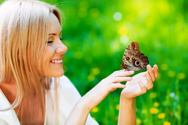 pretty blonde woman playing with the butterfly in the spring park