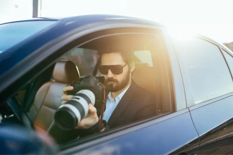 private detective investigating using a binocular while sitting inside the car