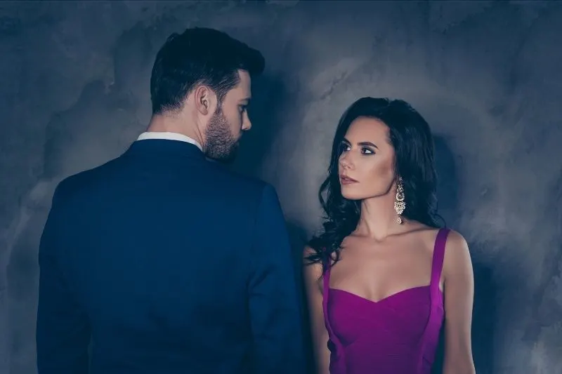 rear view of a man in tuxedo beside a woman in purple dress looking at him