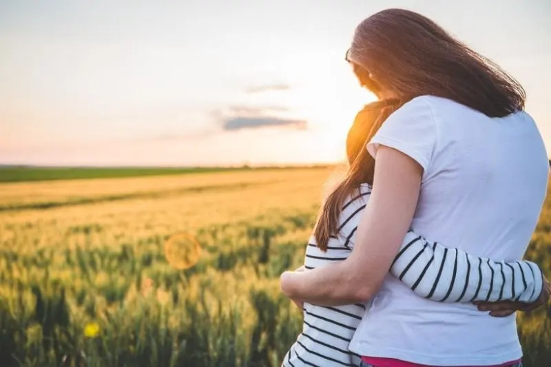 rear view of a mother and daughter hugging each other in the wheat field