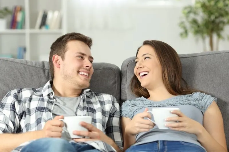 relaxed couple talking with coffee on a sofa inside living room
