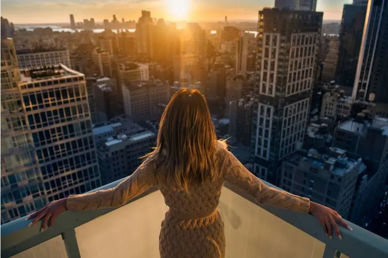 rich woman enjoying the sunset at the top of the high building