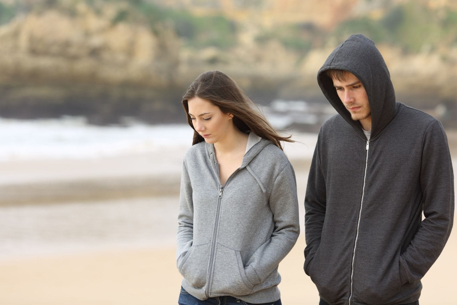coppia triste che cammina sulla spiaggia parlando seriamente