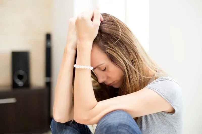 sad woman crying sitting tucked in feet on the floor