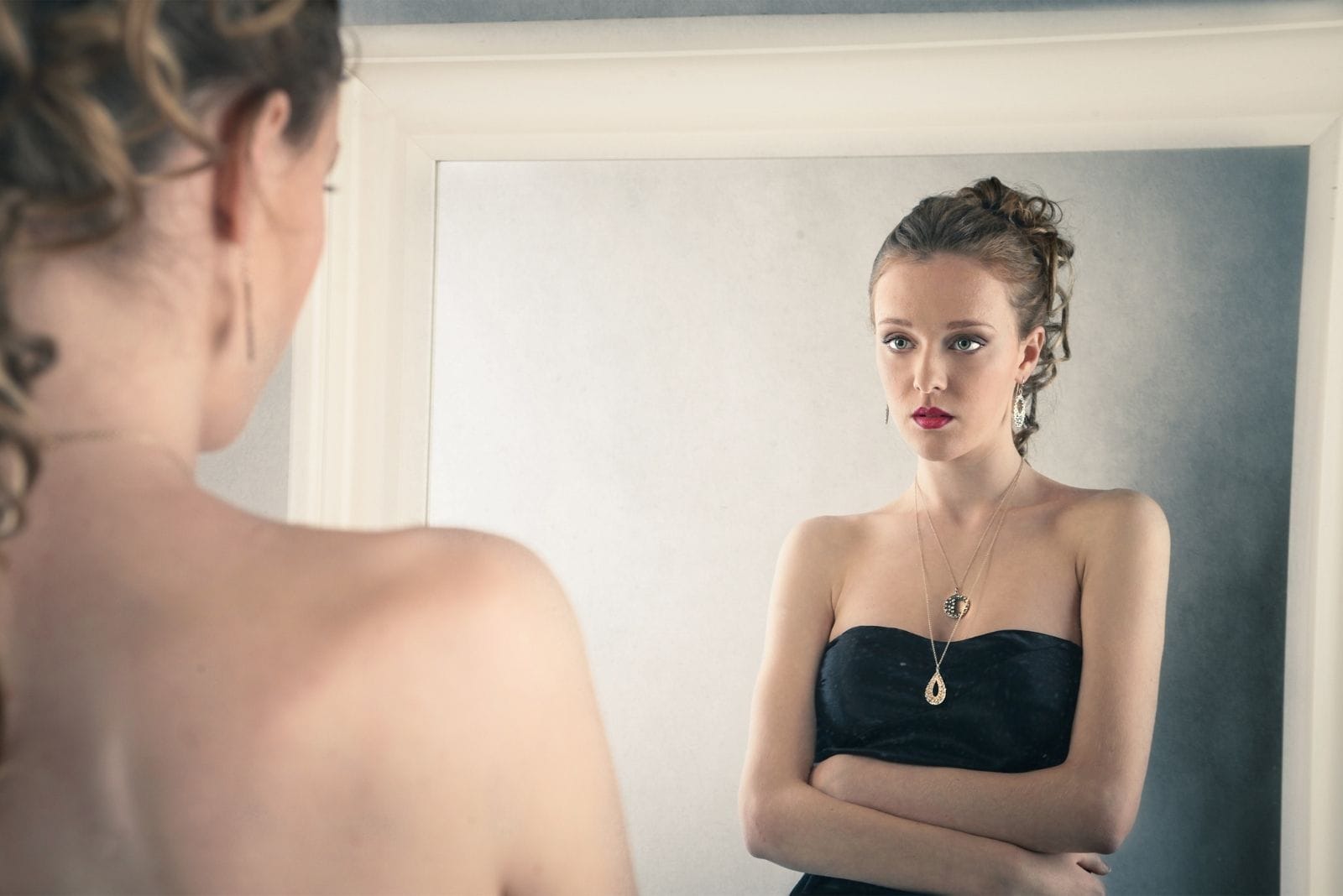 sad woman looking at the mirror wearing black dress 