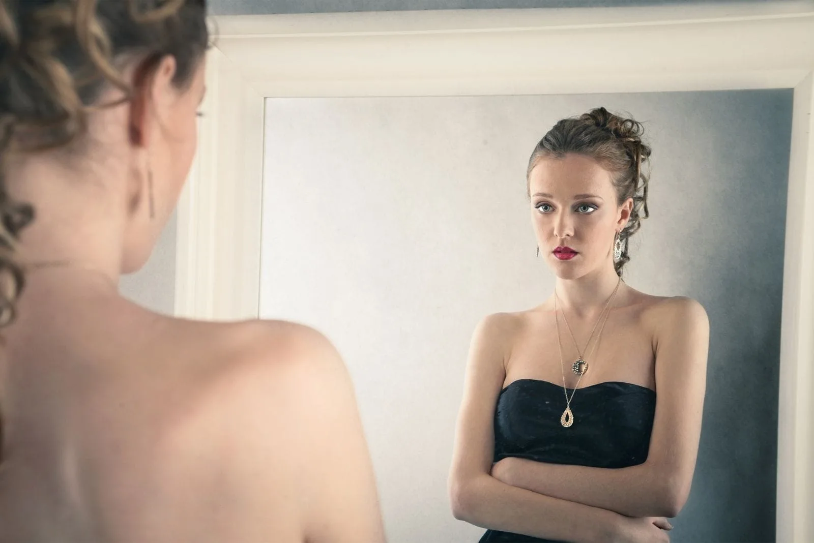 sad woman looking at the mirror wearing black dress 
