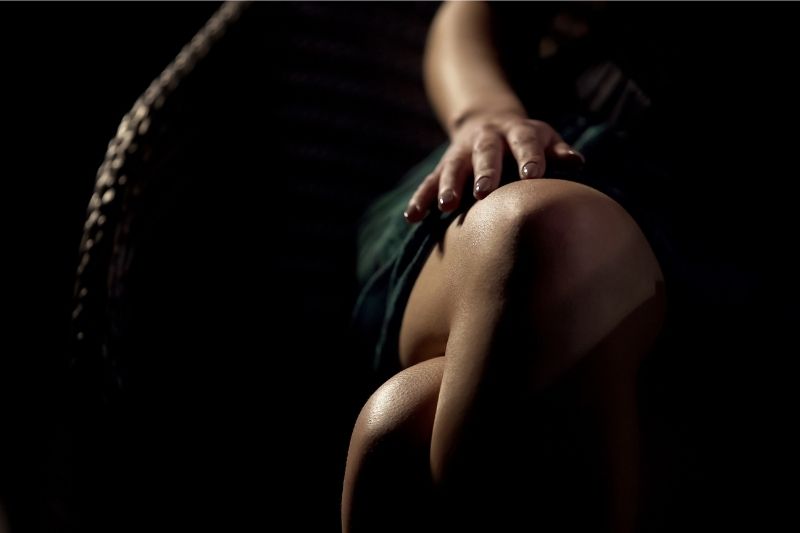 seduction lesson of a woman stroking her legs in dark area in cropped image
