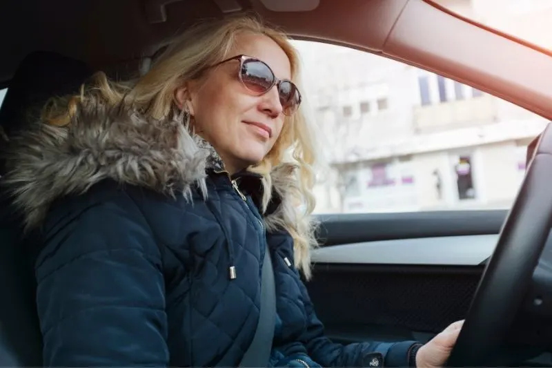 shot of a mature woman driving a car wearing sunglasses and fur coat