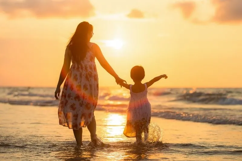 silhouette of a mother and daughter by the sea facing the sun set