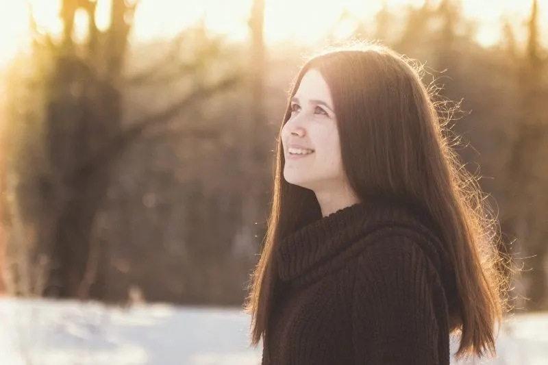 smiling woman outdoors staring upwards during winter