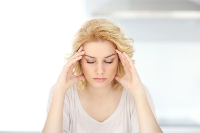 stressed woman closing her eyes feeling stressed inside home