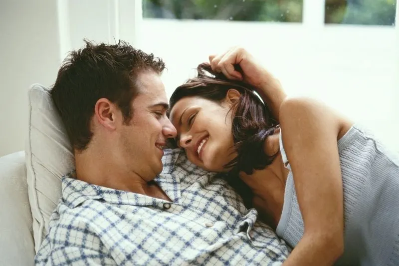 sweet couple cuddling and smiling inside home photo waist up
