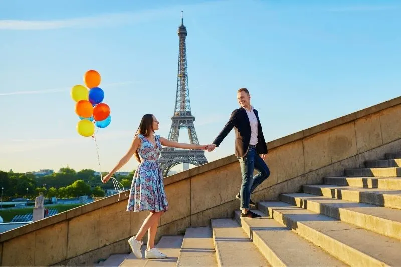 sweet couple hand in hand in the stairs with balloon near the eiffel tower in France
