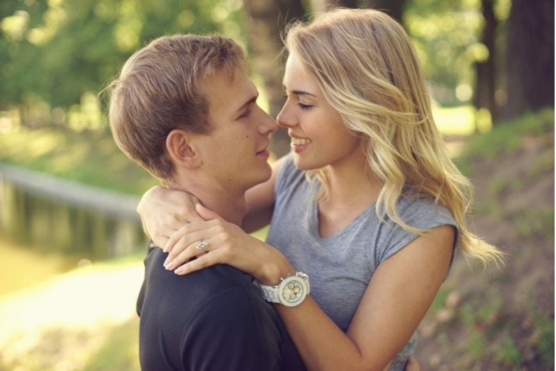 abraço de casal doce sorrindo e doce no parque