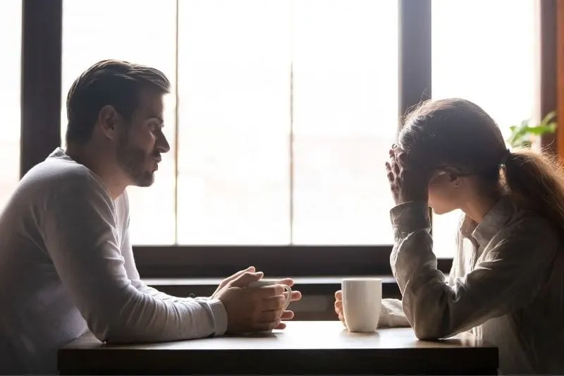 femme bouleversée au café écoutant un homme parler pendant leur pause-café
