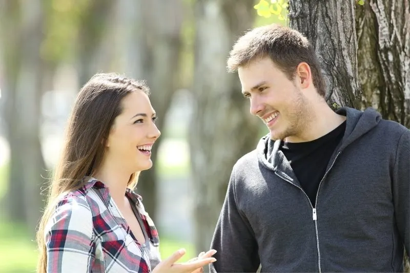 woman and man talking outdoors under a tree in the park
