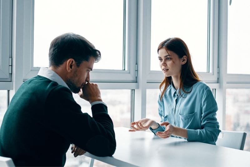 la mujer se enfrenta al hombre por un problema sentados en una mesa hablando