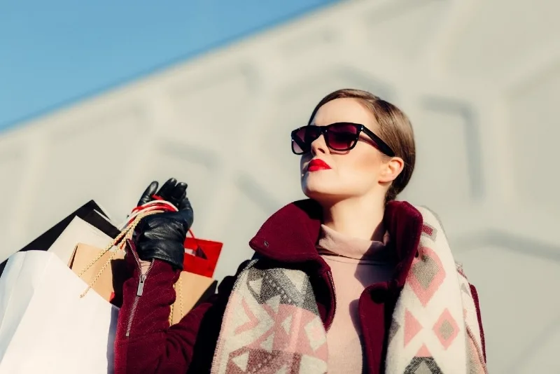 woman with sunglasses holding paper bags outdoor