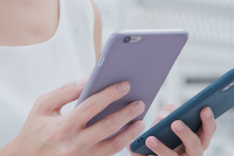 woman holding two cellphones in cropped image