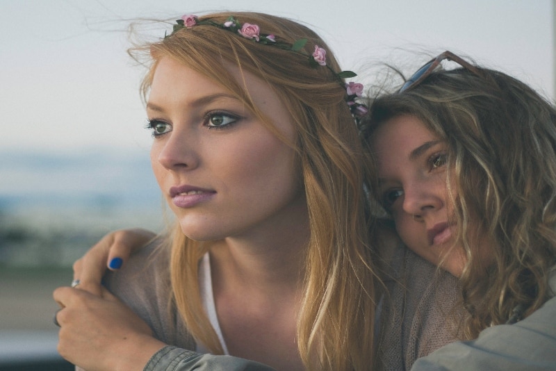 woman hugging woman while sitting outdoor